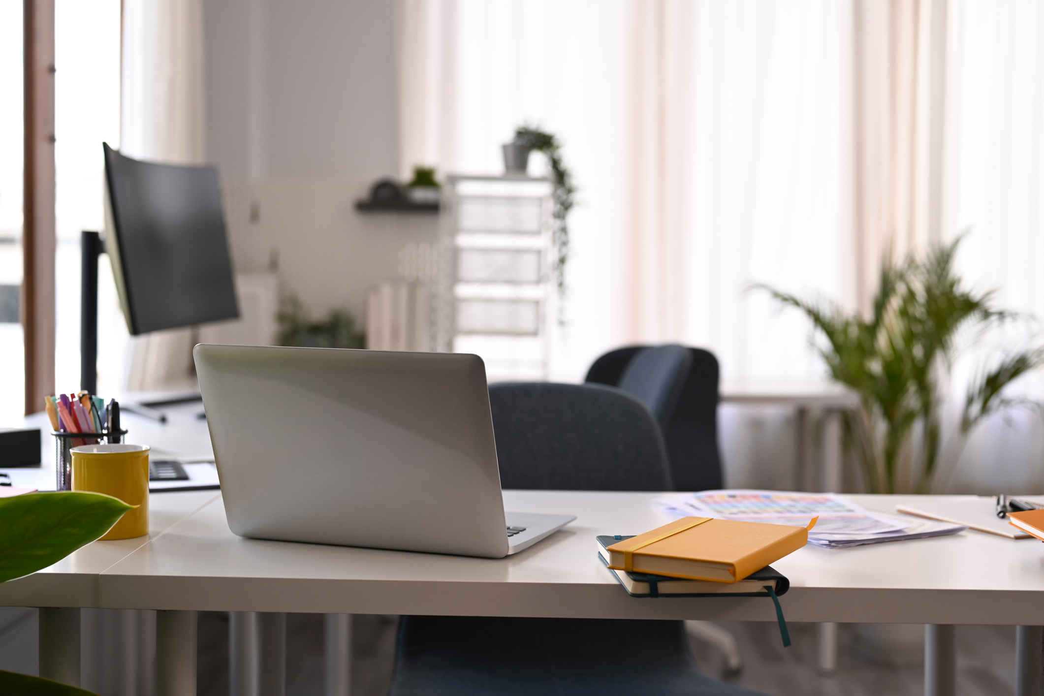 Modern home office interior with laptop computer, documents and various office supplies on white table.